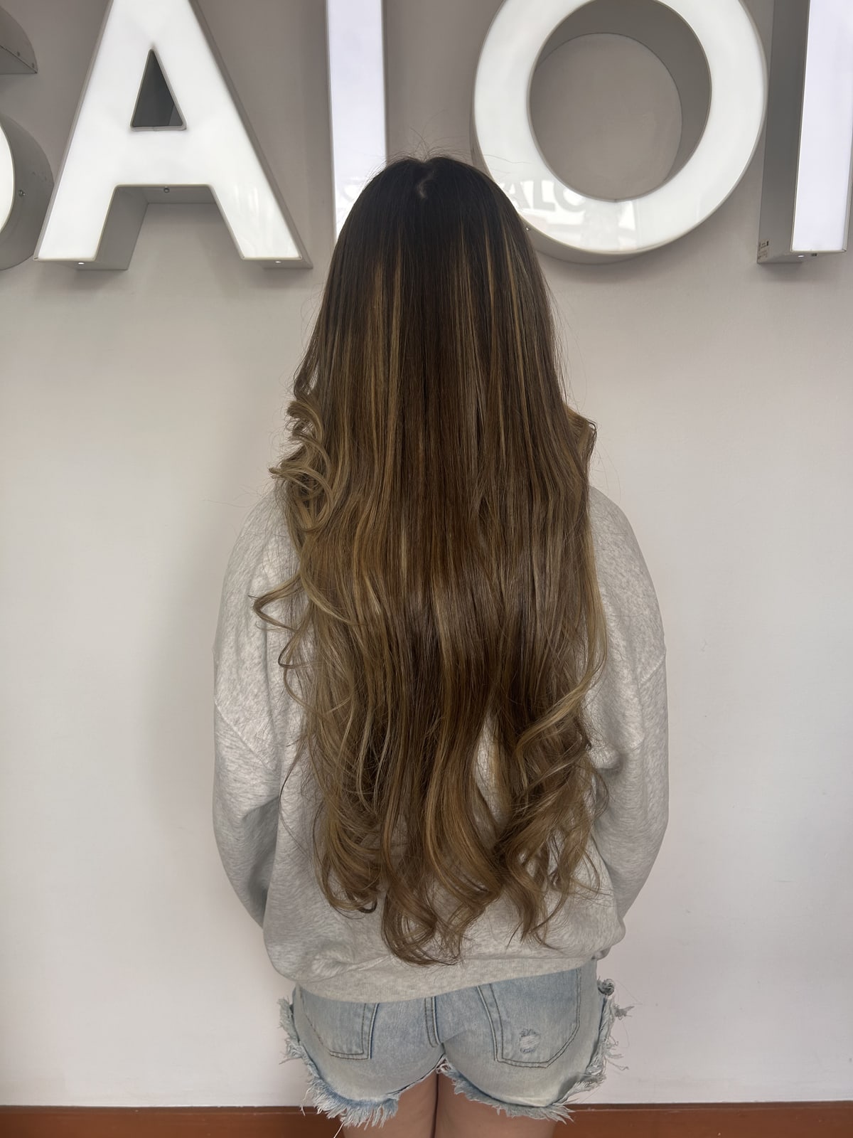 Long wavy blow-dry finish in front of the Frenzy Salon sign
